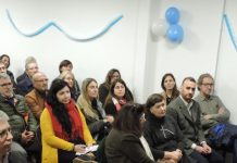 Imagen del acto con Leonardo Curatti hablando al público que se encuentra sentado mirándolo. En la esquina superior izquierda logo del CONICET Mar del Plata.
