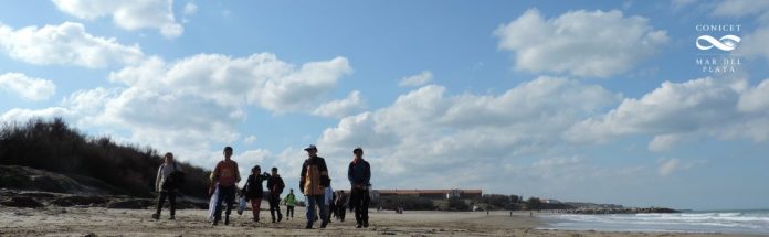 foto de la playa de Chapadmalal con niños caminado en ella. En el borde superior derecho el logo del CONICET Mar del Plata