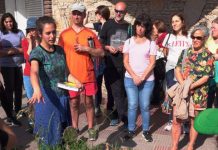 Foto de Vanesa rodeada de otras personas hablando parada al lado de una planta